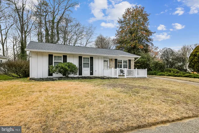 a front view of house with yard and trees in the background