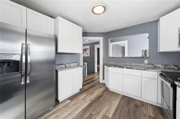 a kitchen with stainless steel appliances granite countertop a stove top oven a sink and white cabinets