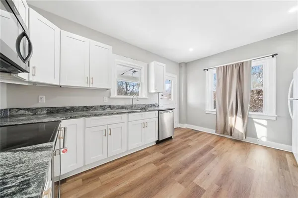 a kitchen with granite countertop a stove a sink and a refrigerator