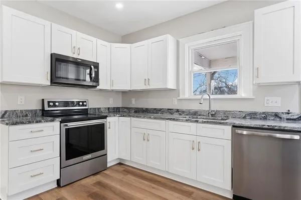 a kitchen with stainless steel appliances granite countertop a stove microwave and sink