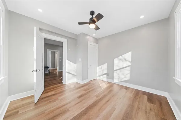 a view of empty room with wooden floor and fan