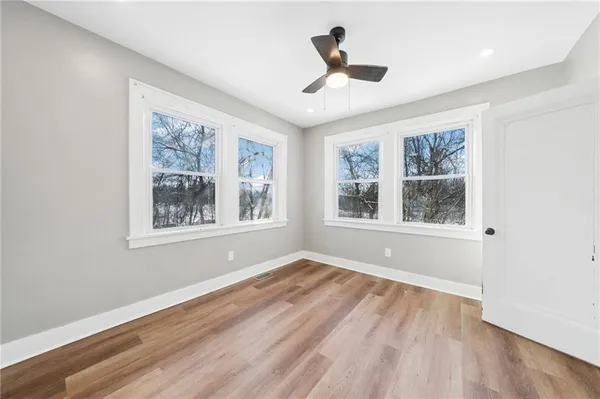 a view of empty room with wooden floor and fan