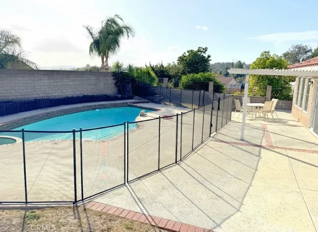 a view of a swimming pool with a patio and a yard