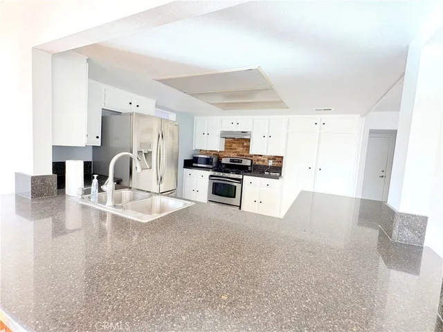 a large kitchen with kitchen island granite countertop a large window and stainless steel appliances