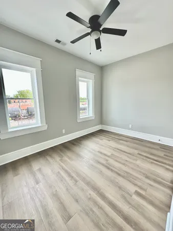 a view of an empty room with window and wooden floor