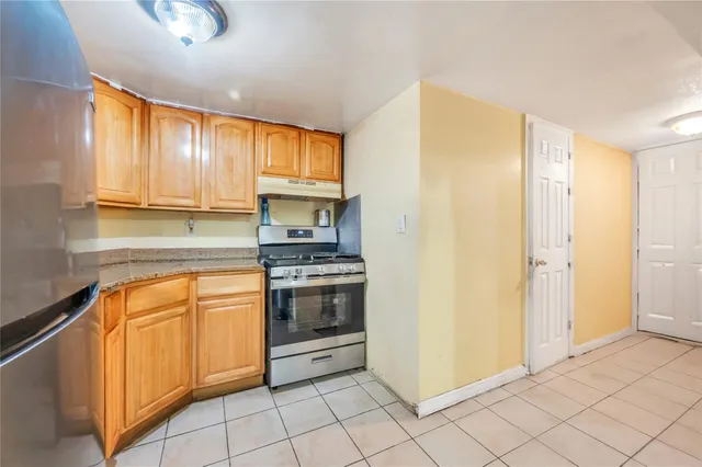 a kitchen with stainless steel appliances granite countertop a refrigerator a stove and a sink with wooden cabinets