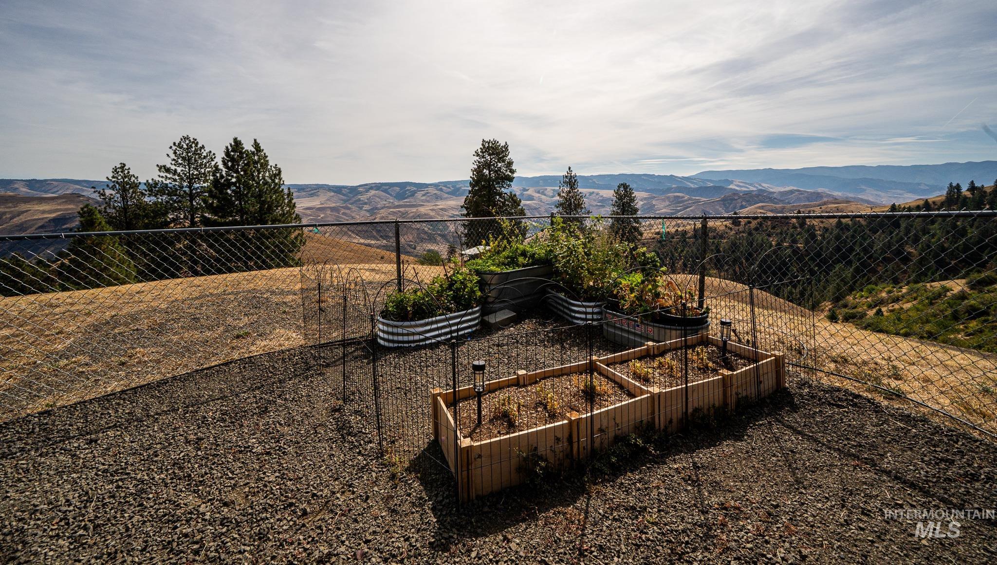 161 Saddle Ridge Road White Bird, ID 83554 - Photo 20 of 49 Expansive green lawn, two-story greenhouse structure, gravel driveway, wood fencing, and covered patio area