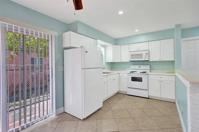 a kitchen with white cabinets and white appliances