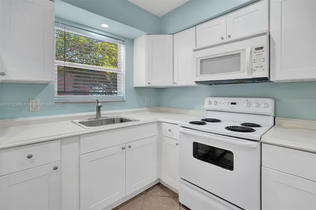 a kitchen with white cabinets appliances and sink