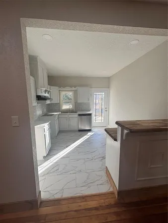 a living room with stainless steel appliances kitchen island granite countertop a refrigerator stove and sink