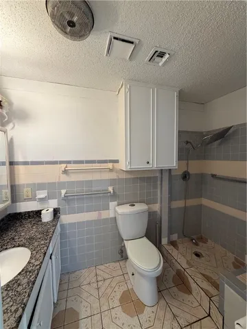 a bathroom with a granite countertop toilet sink and mirror