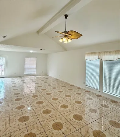 a view of an empty room with window and chandelier fan