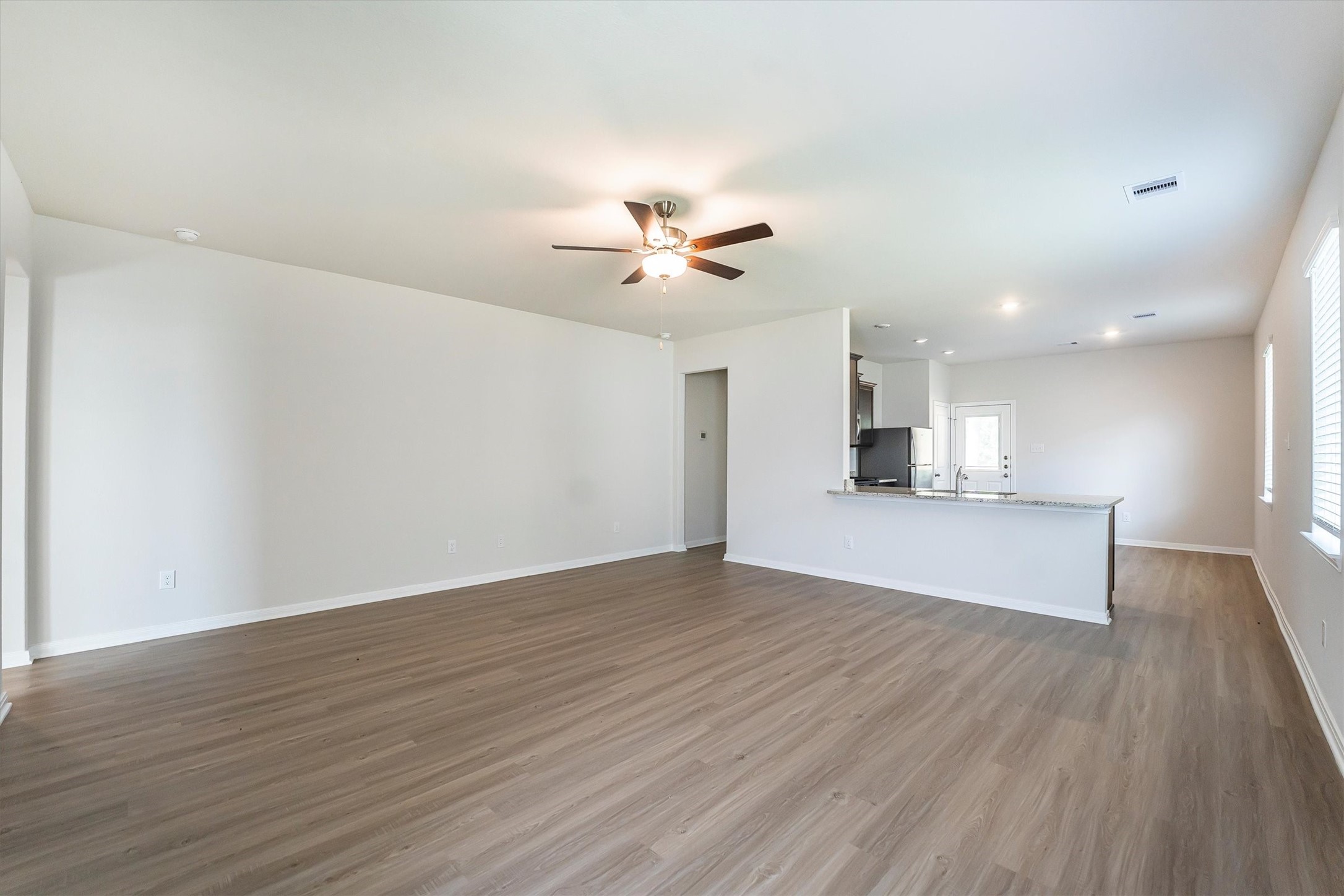 15419 Maple Ter Drive Conroe, TX 77303 - Photo 5 of 32 a view of empty room with wooden floor and kitchen view