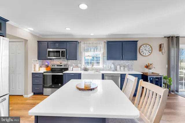 a kitchen with a refrigerator a stove top oven a sink dishwasher and white cabinets with wooden floor