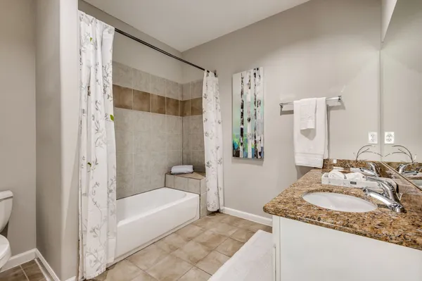 a bathroom with a granite countertop sink and a mirror a bathtub