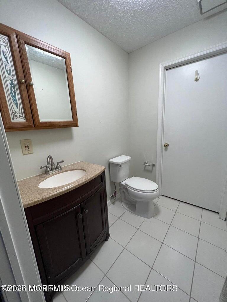 12-7 Phoenix Court Freehold, NJ 07728 - Photo 3 of 12 a bathroom with a granite countertop sink a toilet and a mirror