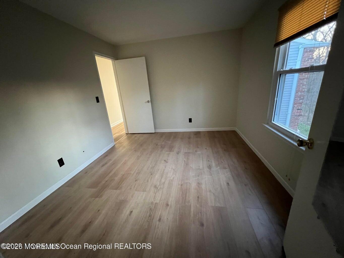 12-7 Phoenix Court Freehold, NJ 07728 - Photo 8 of 12 an empty room with wooden floor and windows