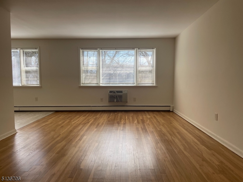 948 Valley Road, Unit A7 Clifton, NJ 07013 - Photo 5 of 9 an empty room with wooden floor and windows