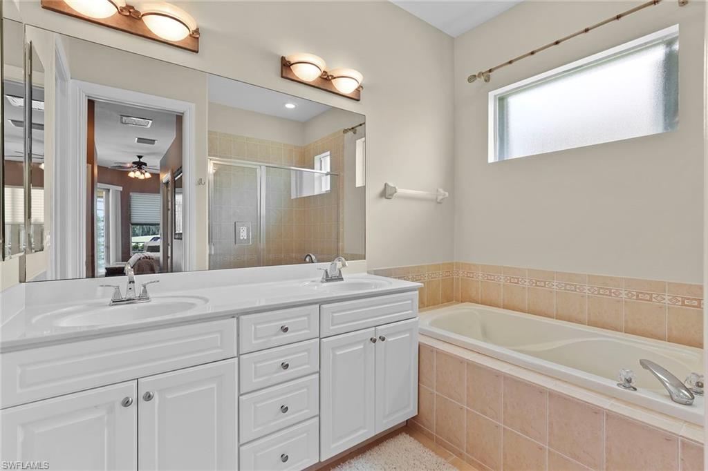 6769 Bent Grass Drive Naples, FL 34113 - Photo 14 of 32 a bathroom with a tub a sink and mirror