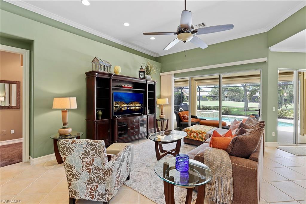 6769 Bent Grass Drive Naples, FL 34113 - Photo 6 of 32 a living room with furniture a flat screen tv and a large window