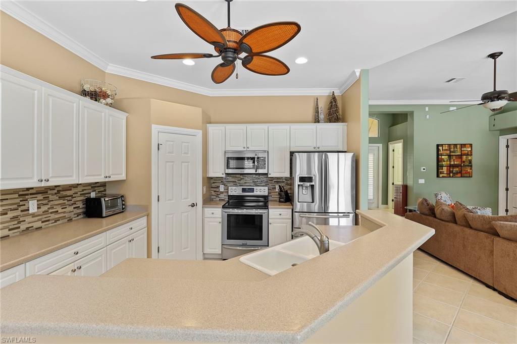 6769 Bent Grass Drive Naples, FL 34113 - Photo 9 of 32 a kitchen with stainless steel appliances kitchen island granite countertop a refrigerator a stove a sink a stove with island cabinets and wooden floor