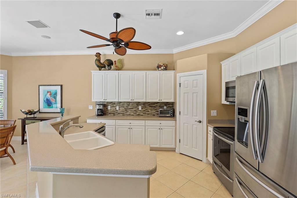 6769 Bent Grass Drive Naples, FL 34113 - Photo 10 of 32 a kitchen with kitchen island a counter top space appliances and cabinets