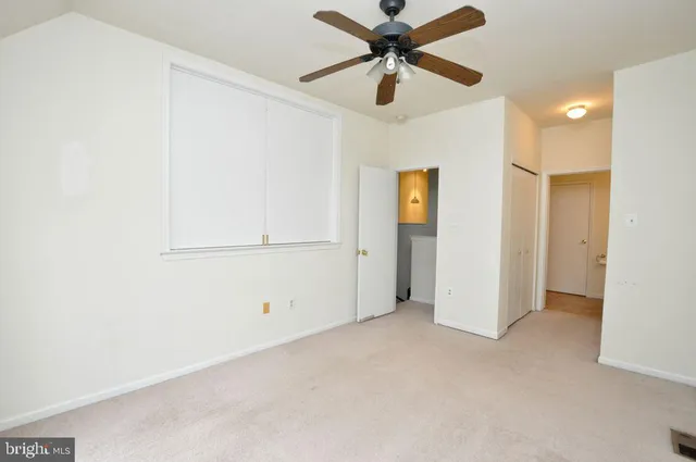 an empty room with closet and a ceiling fan