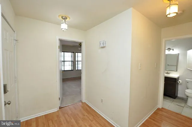 a view of a hallway with wooden floor and a kitchen