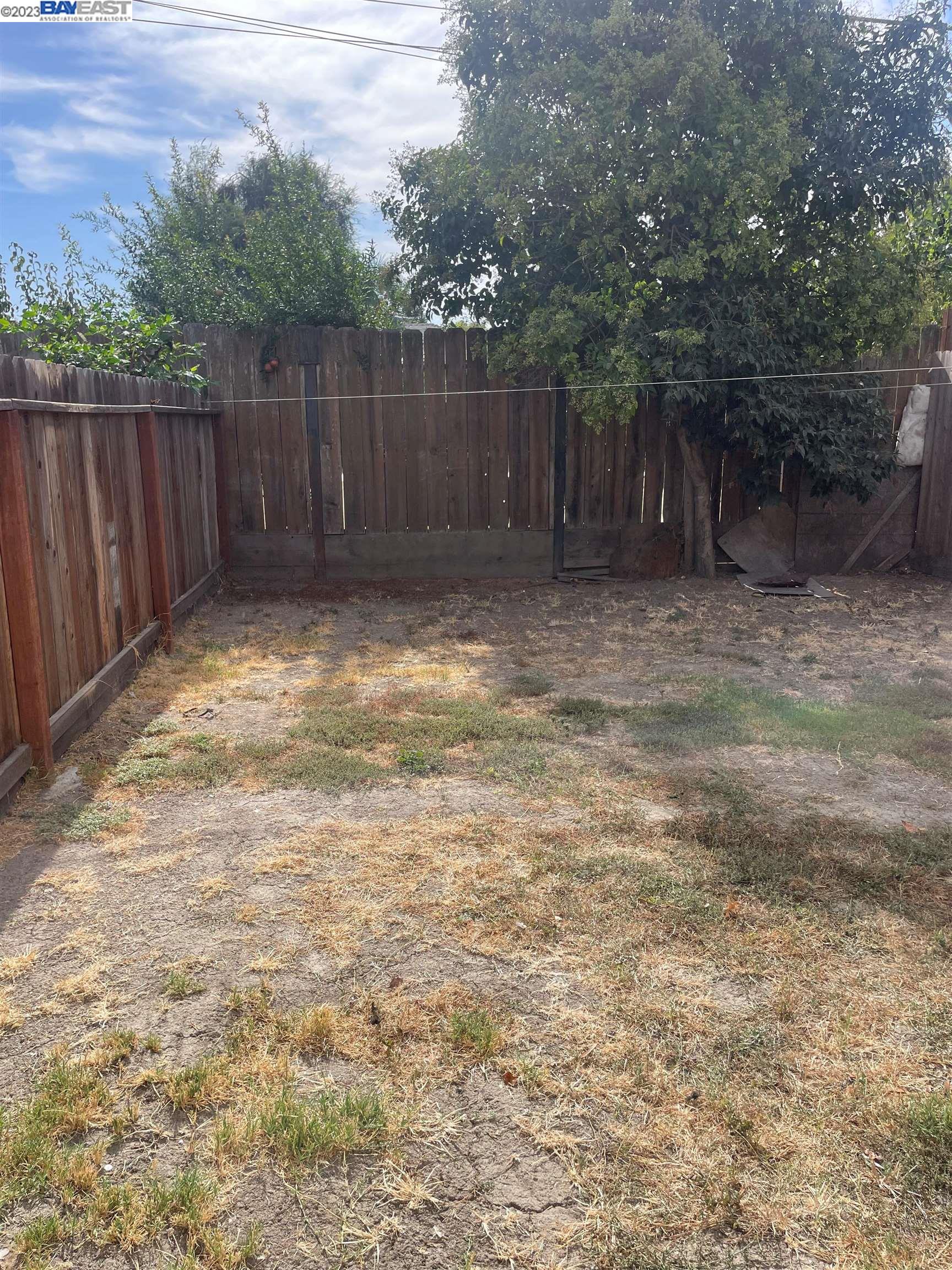 2836 Pixie Drive Stockton, CA 95203 - Photo 8 of 10 a view of a backyard with large trees and wooden fence