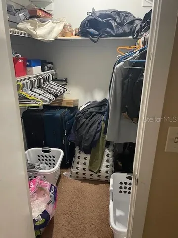 a view of walk in closet with clothes and shoes