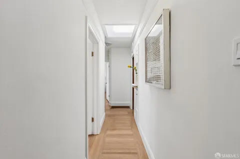 a view of a hallway with wooden floor and a bathroom