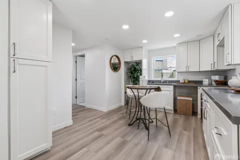 a kitchen with stainless steel appliances kitchen island granite countertop a table chairs sink and cabinets