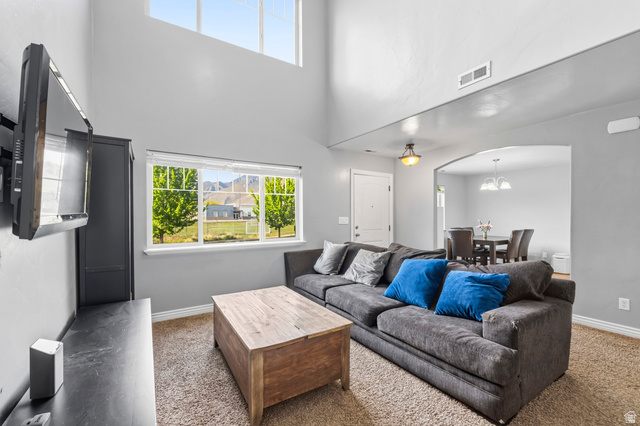1165 West 100 South Springville, UT 84663 - Photo 5 of 28 Carpeted living room with arched walkways, healthy amount of natural light, and a high ceiling