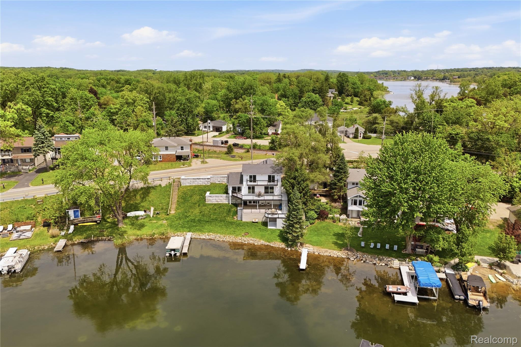 7217 Andersonville Road Clarkston, MI 48346 - Photo 52 of 65 Waterfront property featuring multiple boat docks, a large multi-level deck, and a gently sloping grassy lawn