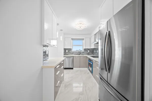 a kitchen with stainless steel appliances granite countertop a refrigerator a sink and white cabinets