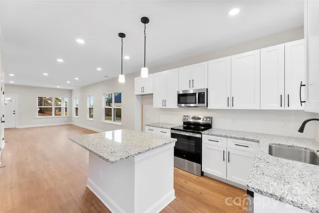a kitchen with stainless steel appliances granite countertop a sink stove and microwave