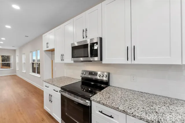 a kitchen with stainless steel appliances granite countertop a stove a sink and a microwave