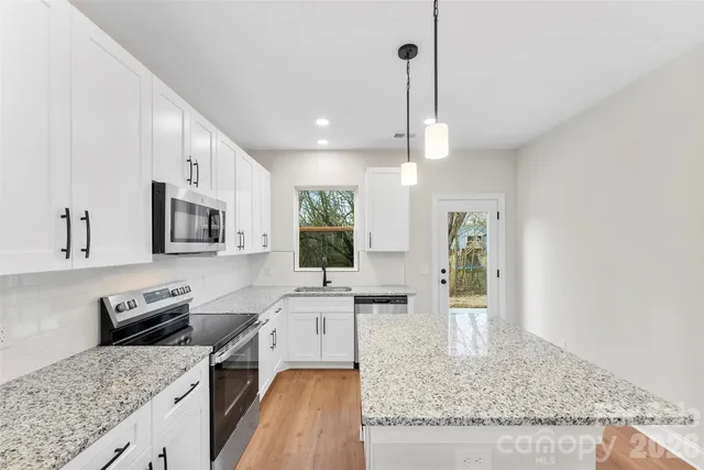 a kitchen with stainless steel appliances granite countertop a sink stove and refrigerator