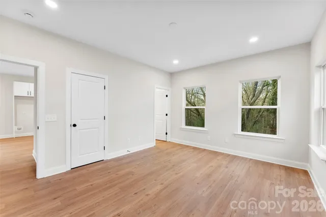 a view of an empty room with wooden floor and windows