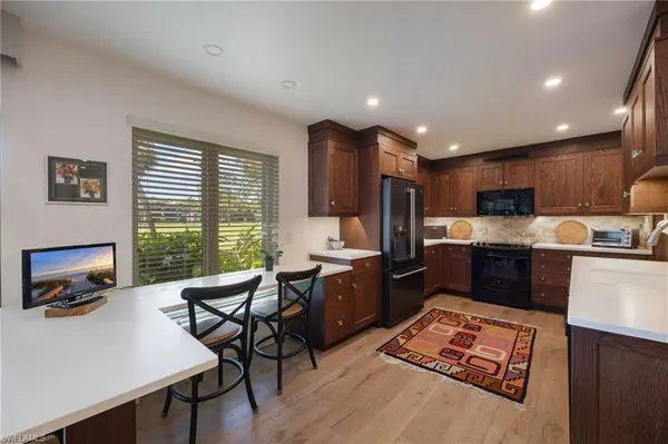 a kitchen with stainless steel appliances granite countertop a stove top oven a sink dishwasher a dining table and chairs with wooden floor