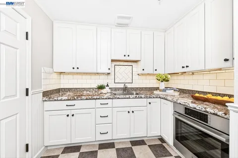 a kitchen with granite countertop white cabinets and white appliances