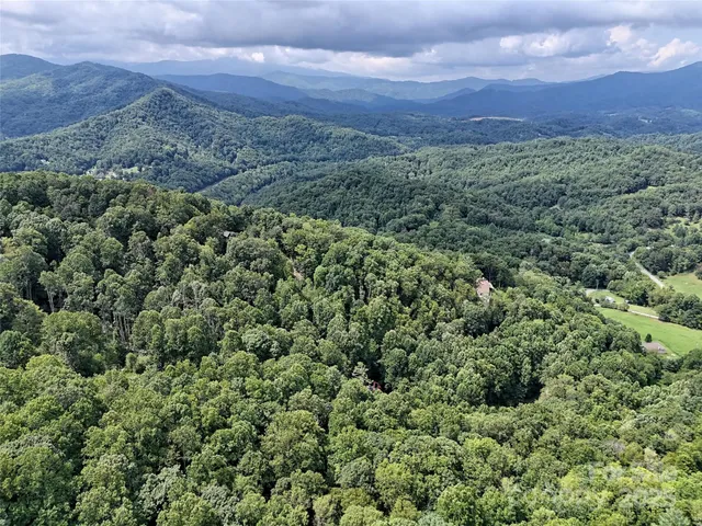 an aerial view of a houses with a yard and mountain