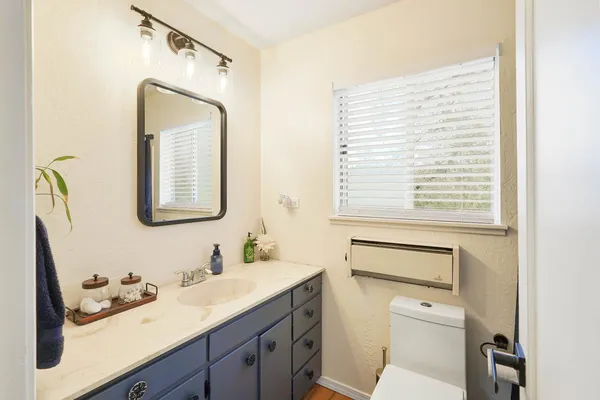 a bathroom with a granite countertop toilet a sink and a mirror