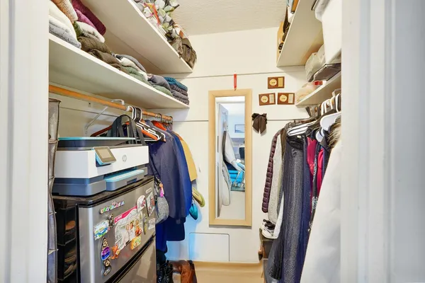 a view of walk in closet with clothes and shoes