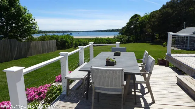 a view of a patio with table and chairs potted plants with wooden floor and fence