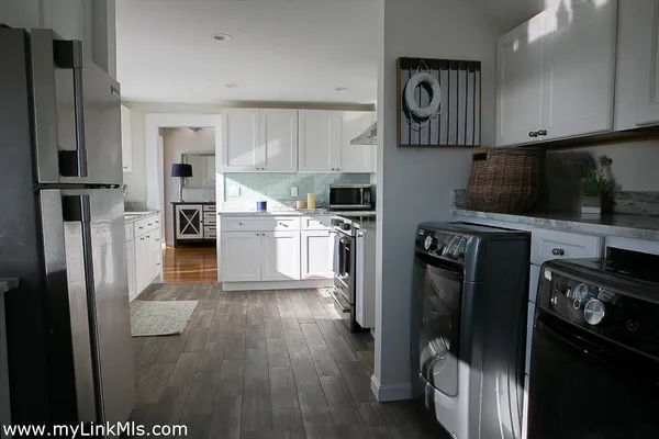 a kitchen with stainless steel appliances granite countertop a refrigerator stove and white cabinets