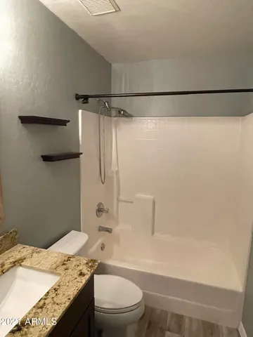 a bathroom with a granite countertop bathtub shower sink vanity and toilet