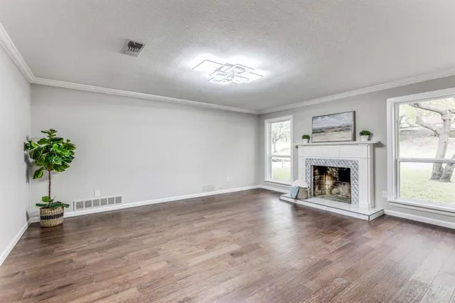 an empty room with wooden floor a fireplace and windows