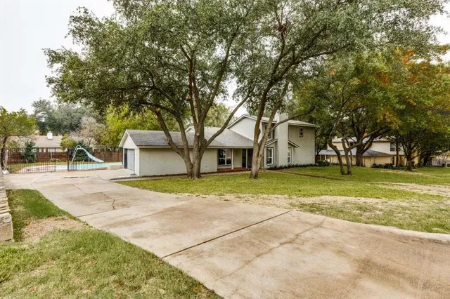 a view of a house with a yard and large trees