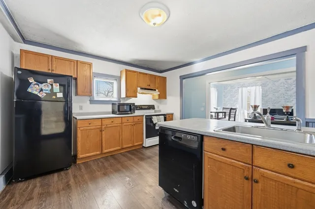 a kitchen with stainless steel appliances granite countertop a refrigerator a sink dishwasher a stove and white countertops with wooden floor